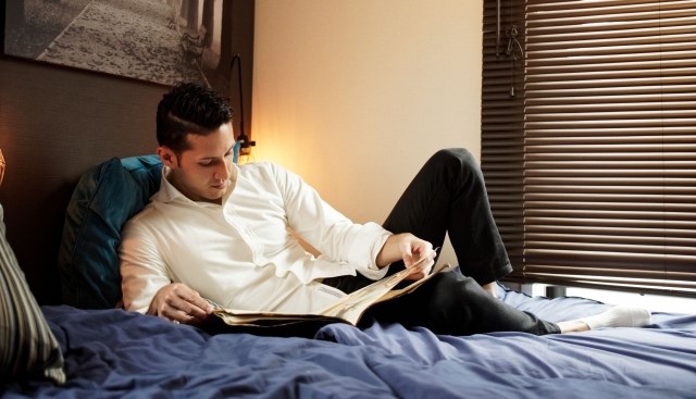 ベッドで横になり本を読む男性